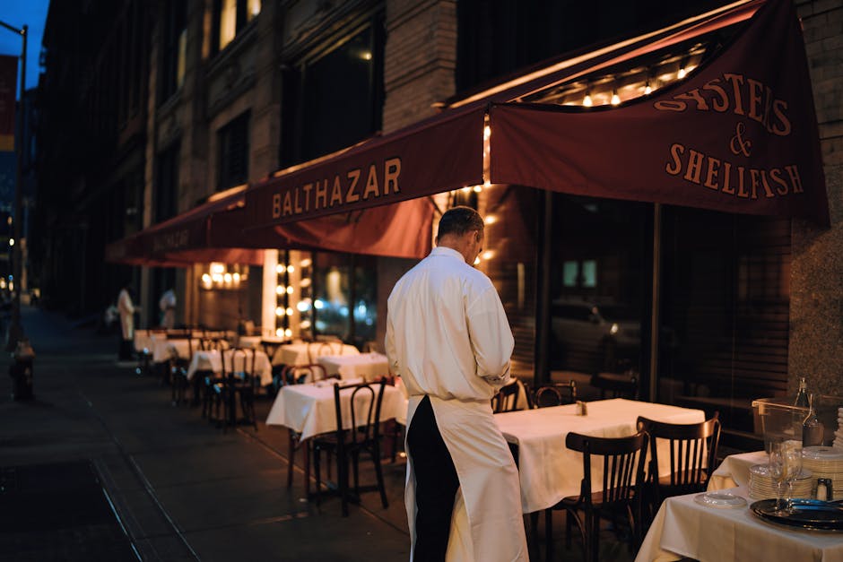 Elegant outdoor dining area at night with waitstaff preparing tables