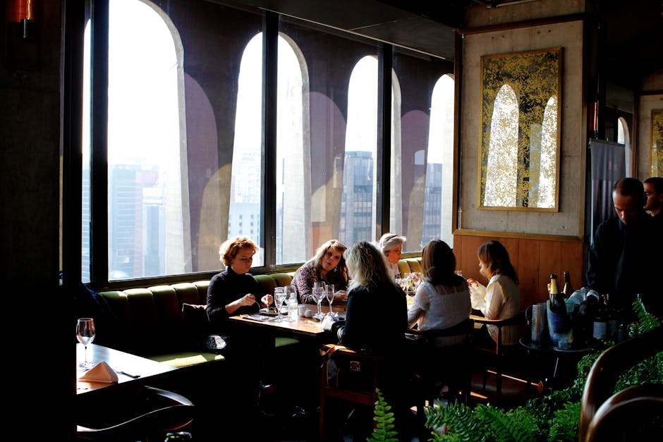 Group of adults enjoying a meal in a stylish city restaurant with large windows