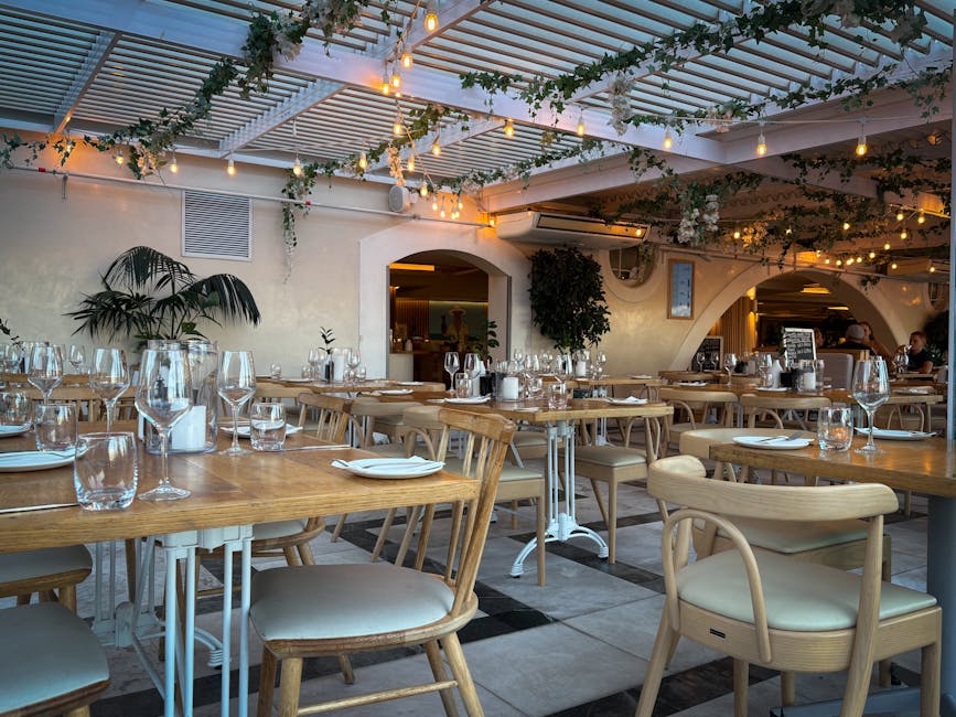 Elegant indoor restaurant setting with wooden furniture, warm lighting, and decorative foliage.