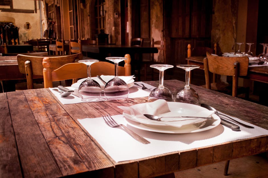 A rustic restaurant table set with wine glasses and cutlery invites guests to dine